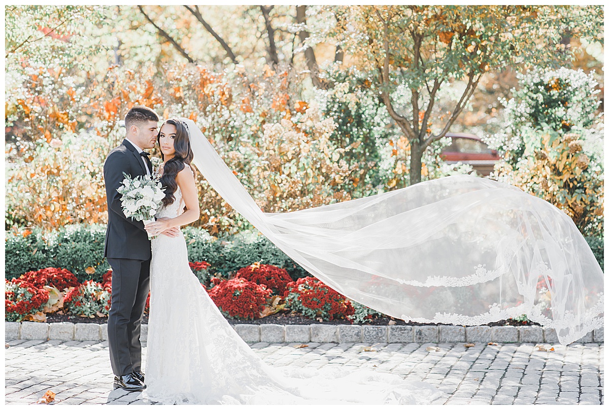 bride and groom with fall colors veil flying in air 