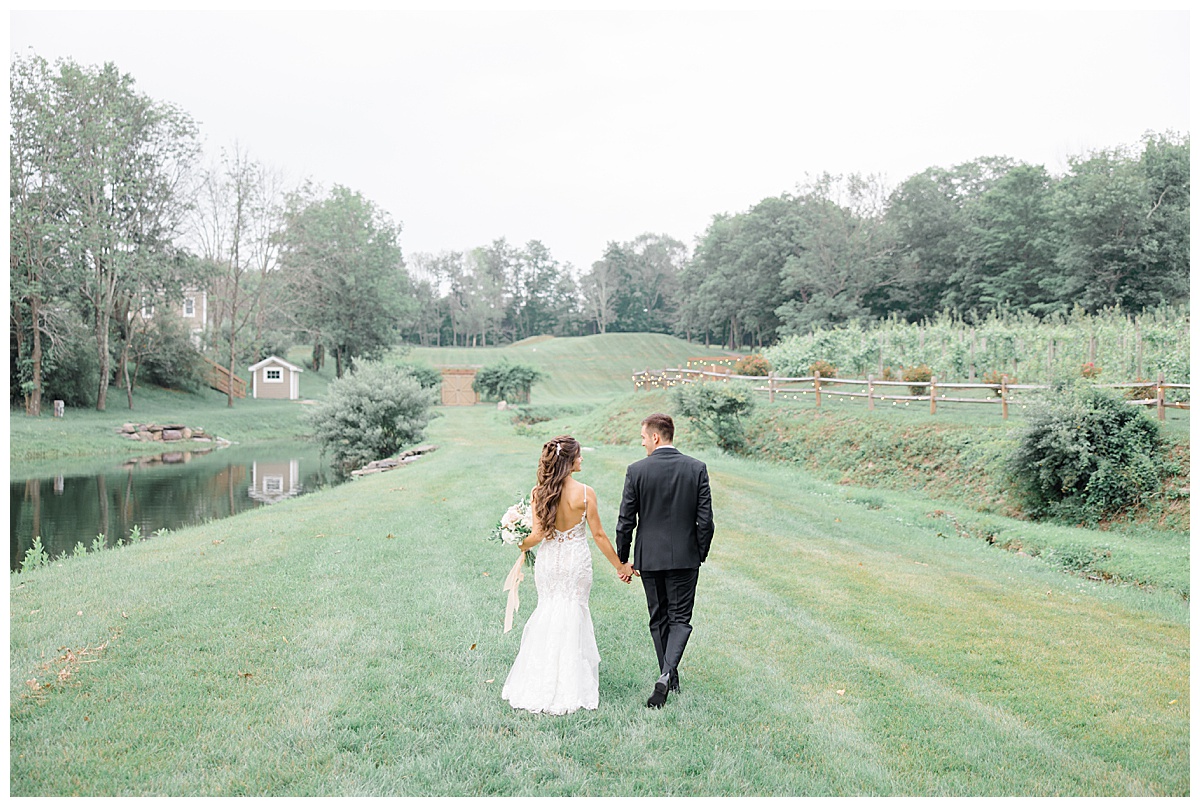bride and groom walking in field 