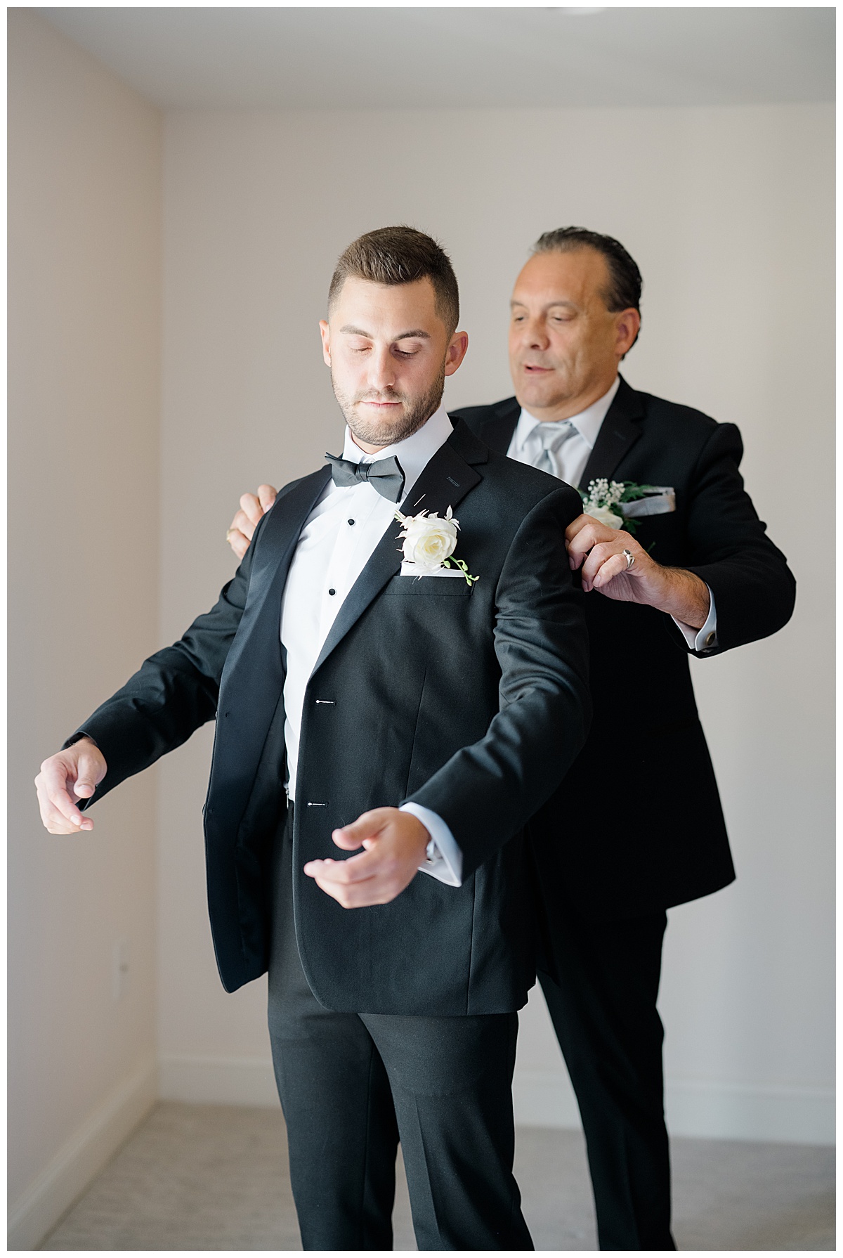 Dad helping groom get dressed on wedding day. 