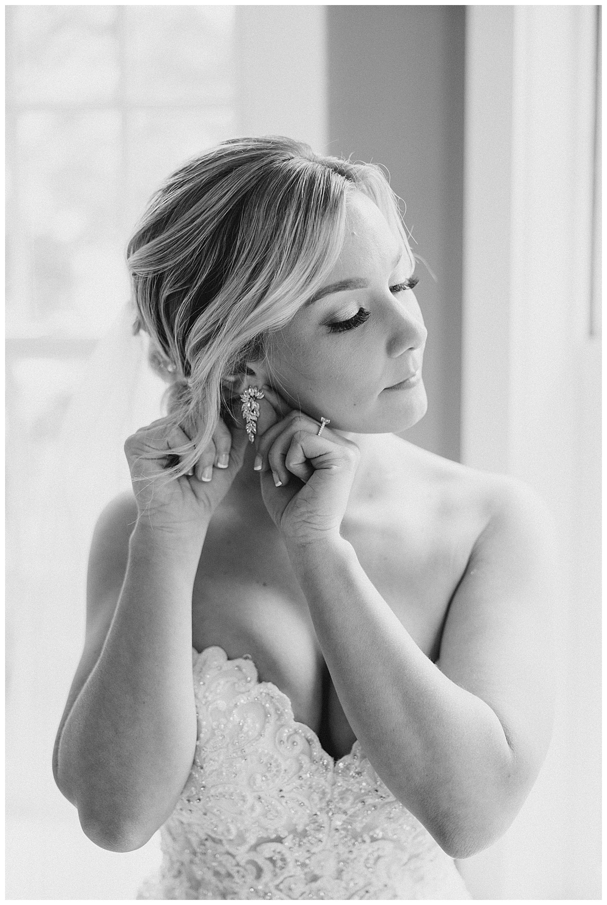 Black and white of bride putting on earring 