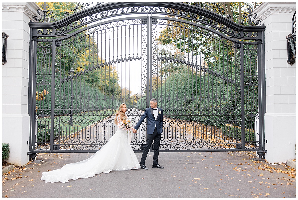 Bride and groom walking in front of iron gates at Shadowbrook at Shrewsbury. 