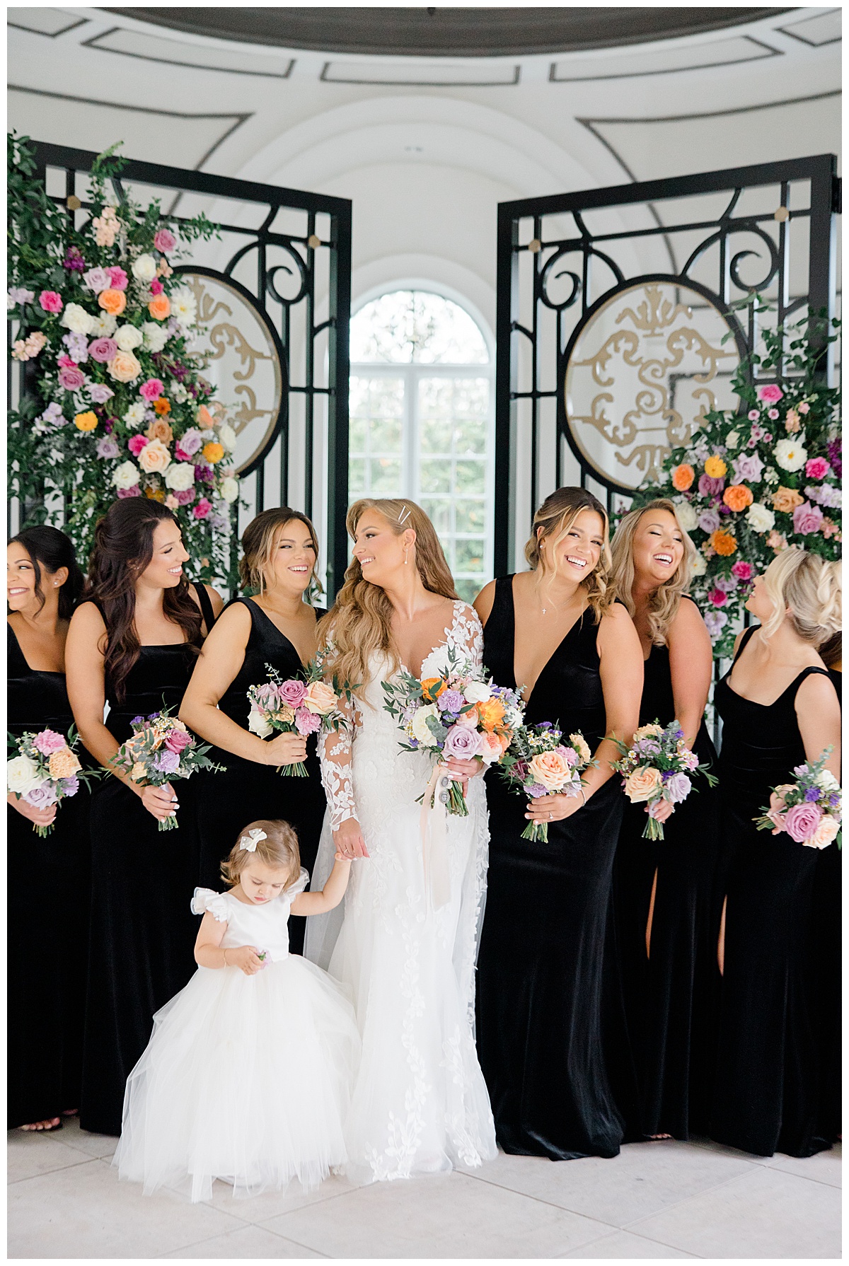 Bridal party laughing at each other in black velvet winter dresses. 