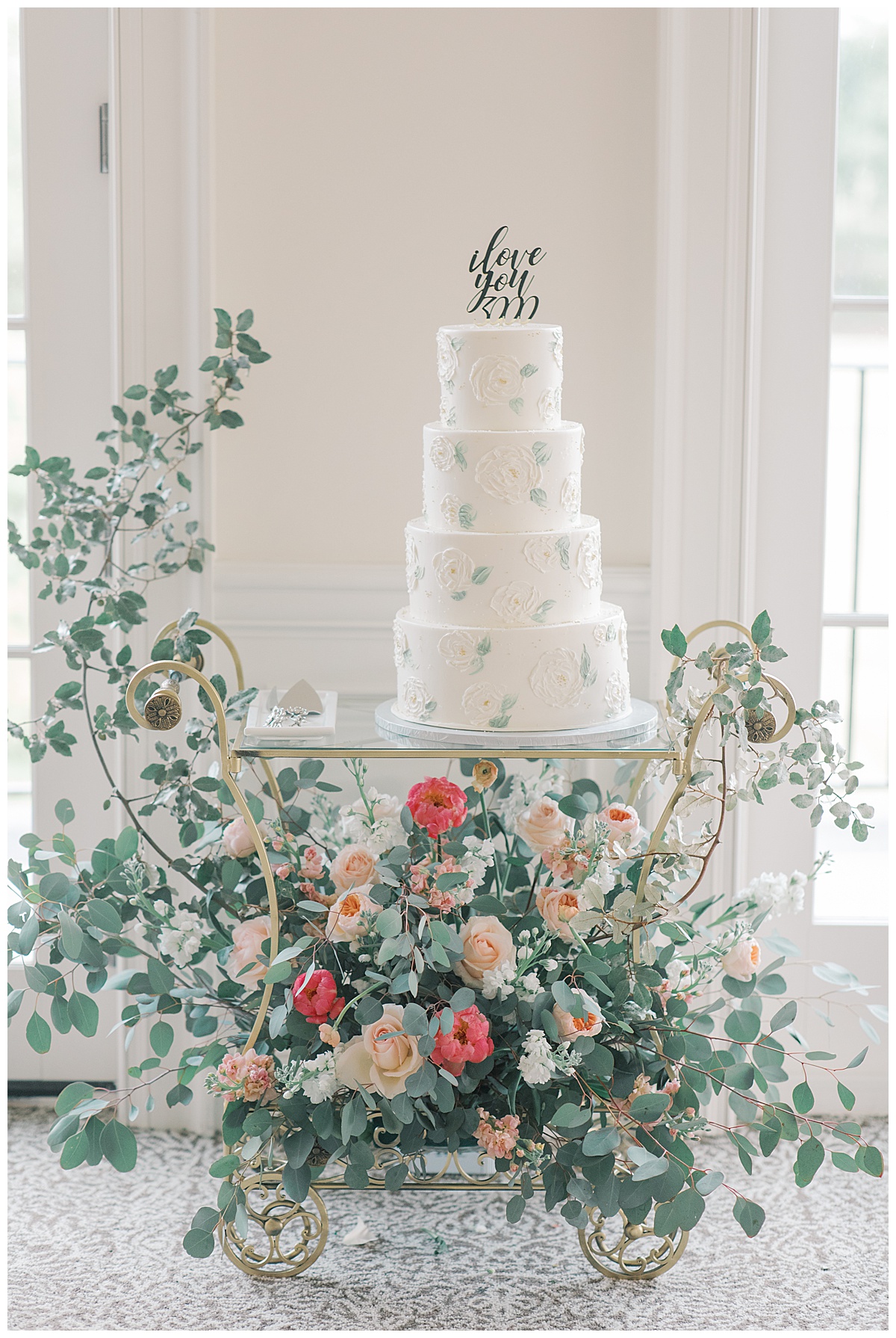 beautiful lush wedding cake with cart and greenery 