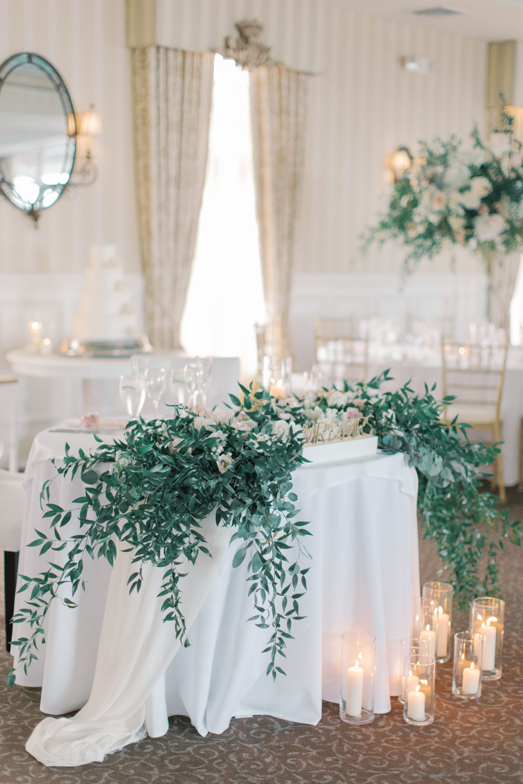 Sweetheart table with draping greenery and lots of candles. 