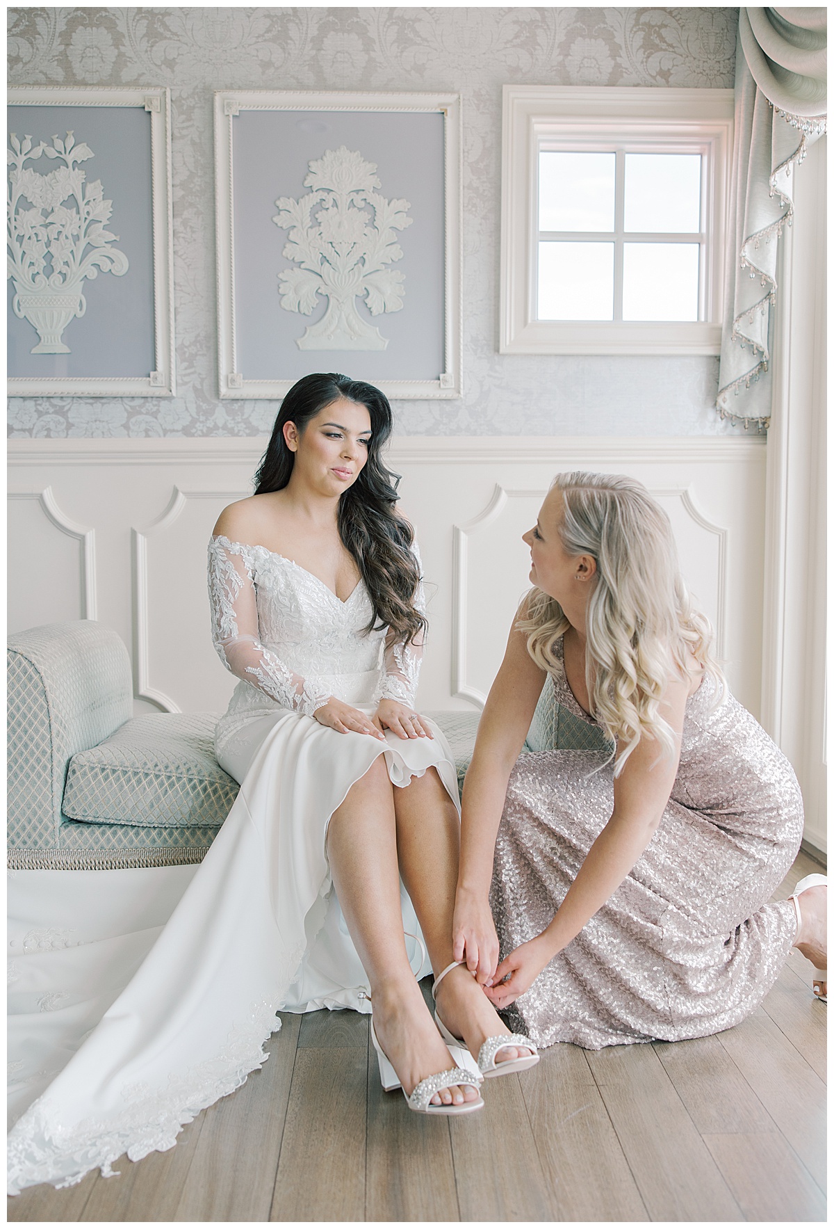Maid of honor helping bride into her shoes on wedding day. 