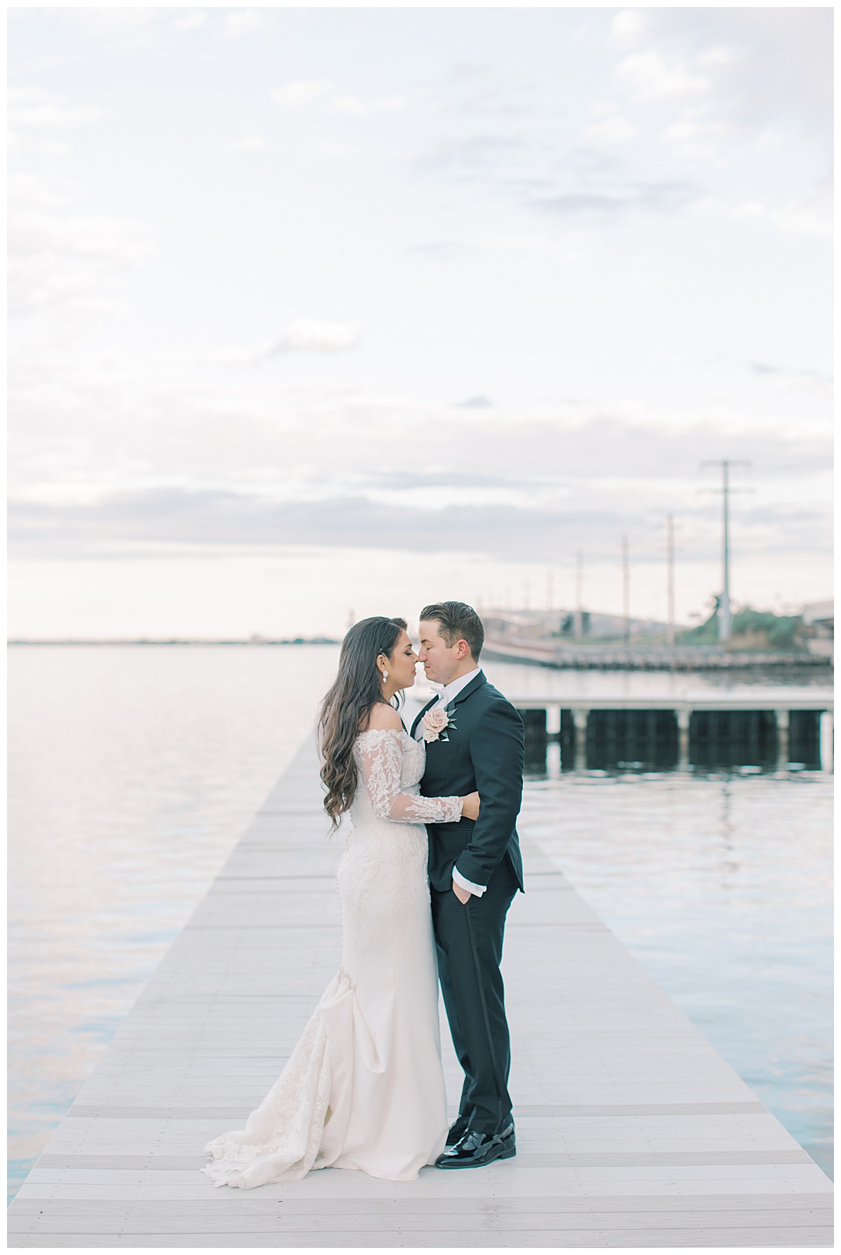 Bride and groom admiring each other with the bay behind them and a pink sky sunset. 