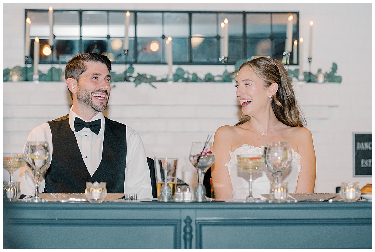 bride and groom share a laugh as they listen to toasts on wedding day 