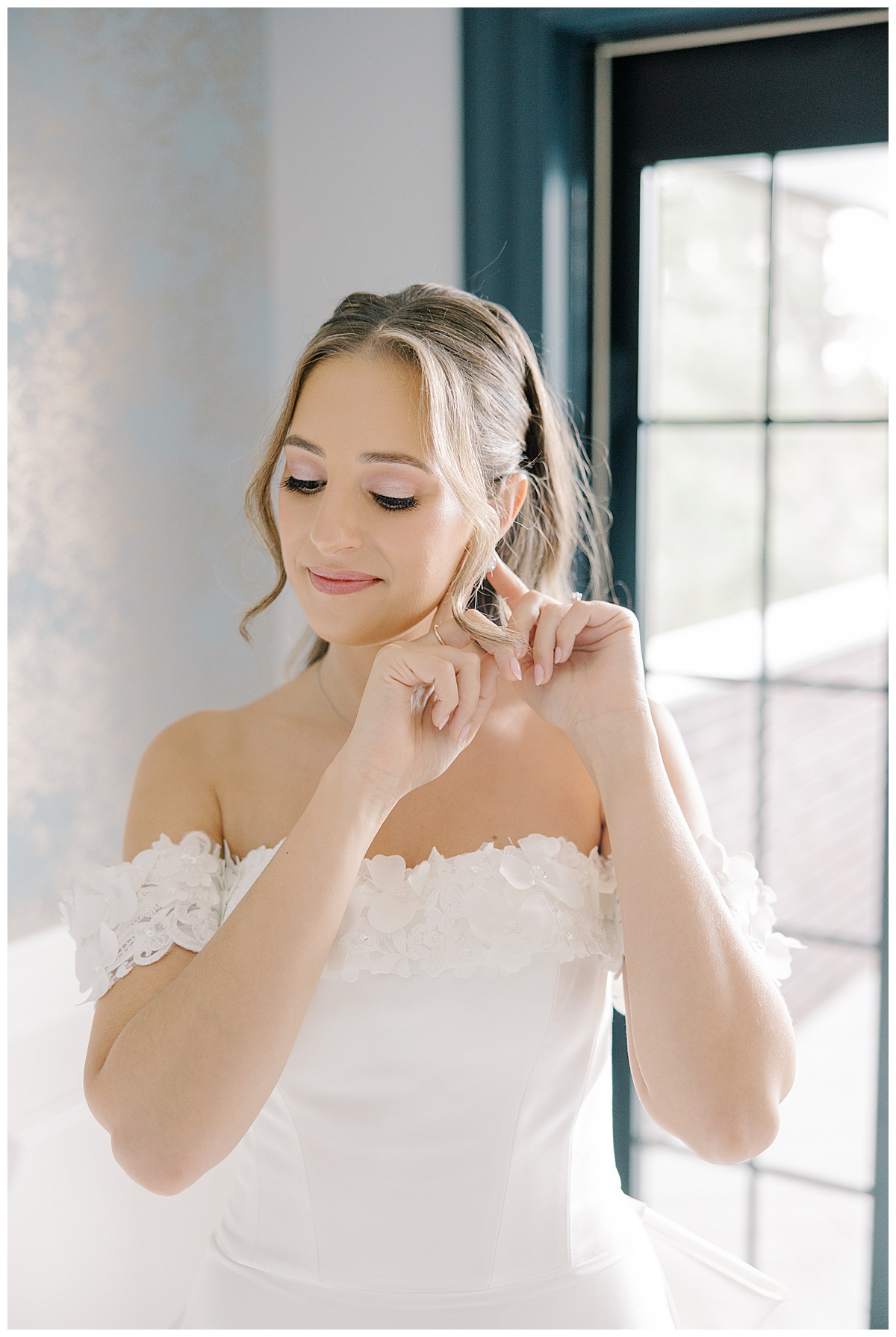 light and airy bridal portraits of bride putting on earring on wedding day 