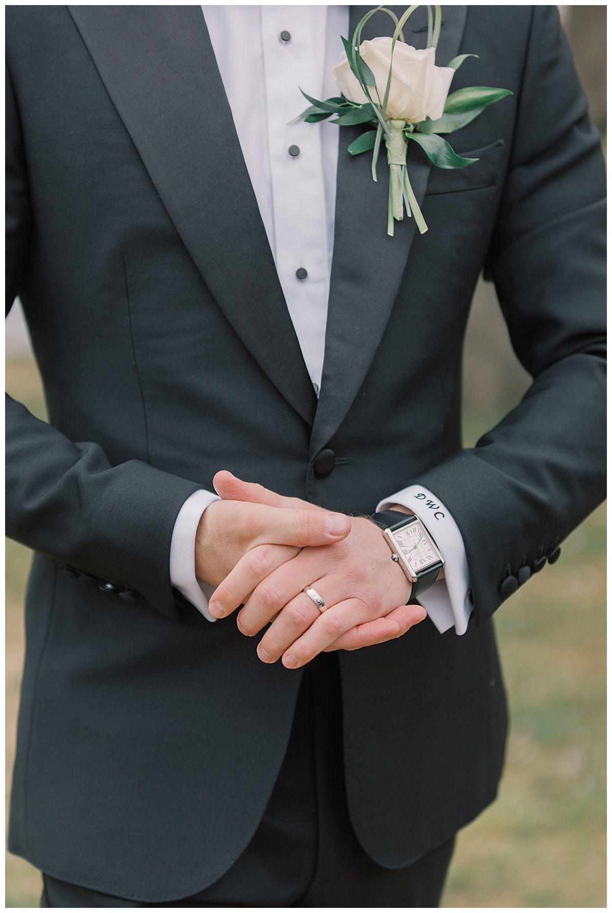 Groom shows off custom tuxedo with embroidered initials on sleeve and Cartier watch. 