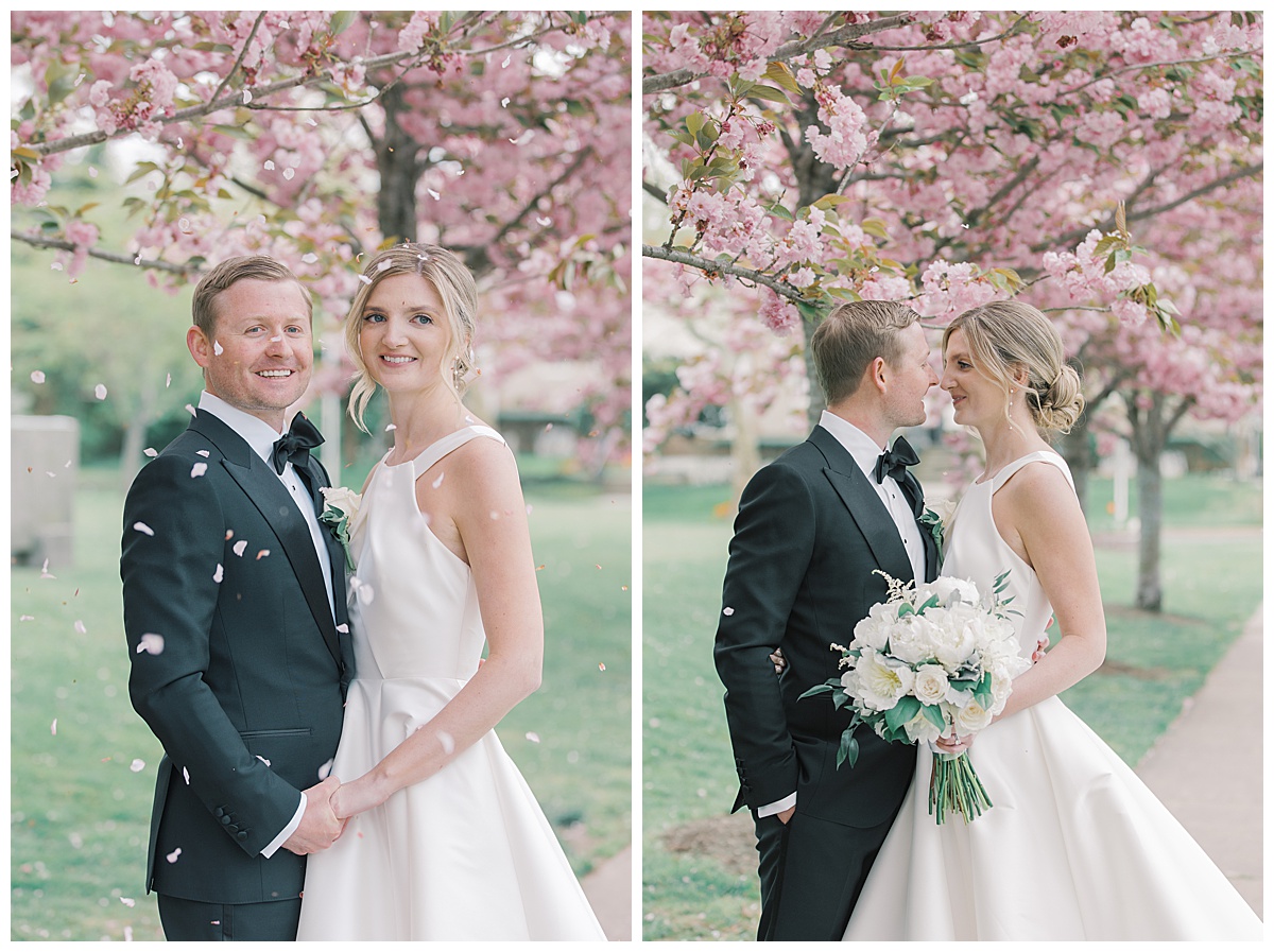 Bride and groom smile together while cherry blossoms fall at The Mill Lakeside Manor. 