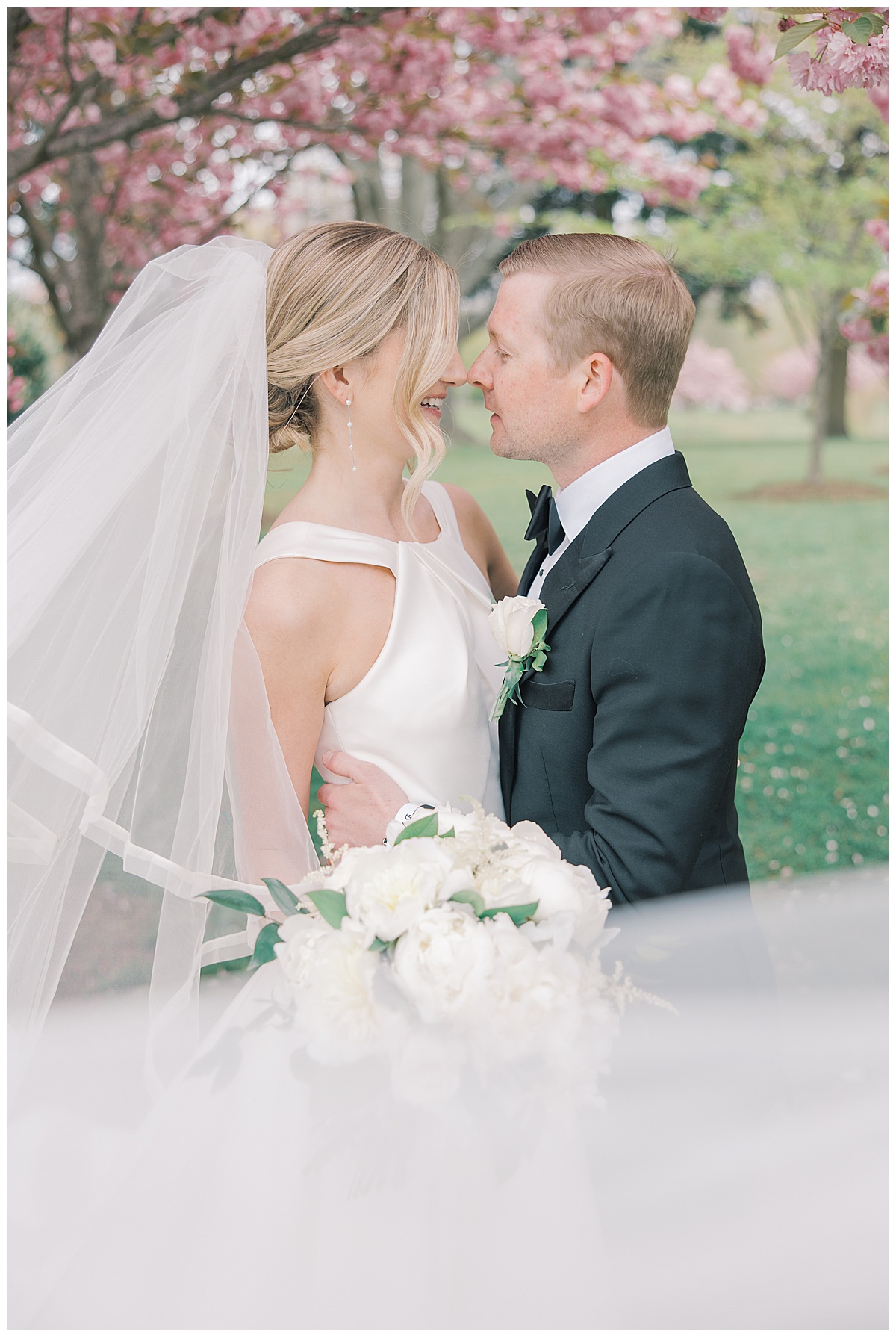 Bride and groom with veil swept in front of them during spring wedding at The Mill Lakeside Manor. 