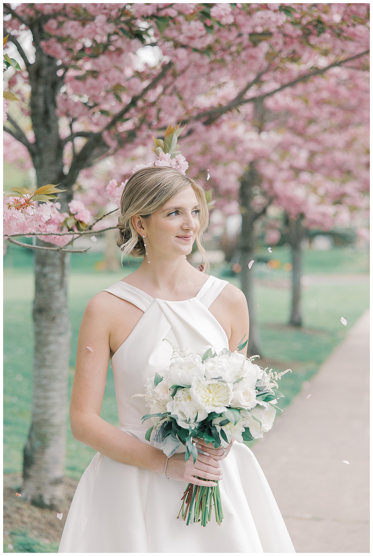 Bride looking off to the side with beautiful cherry blossoms sprinkling on her at The Mill Lakeside Manor. 