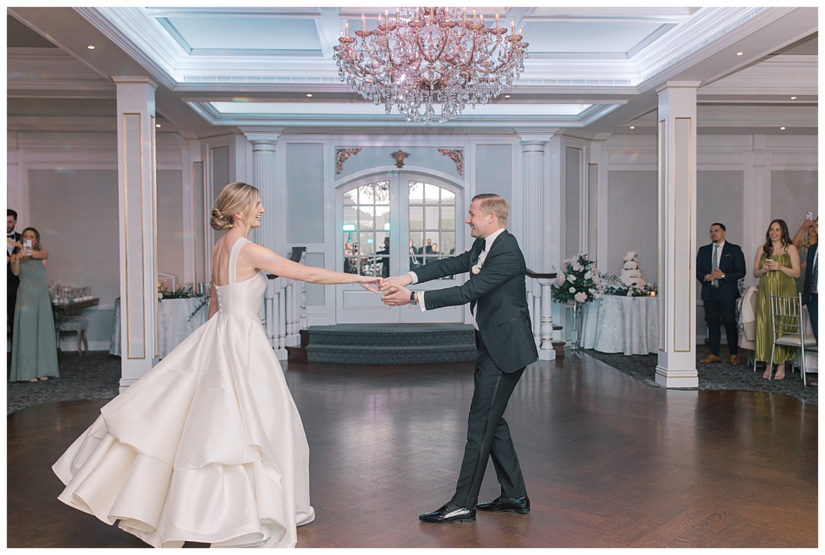Groom twirls bride on dance floor at The Mill Lakeside Manor. 
