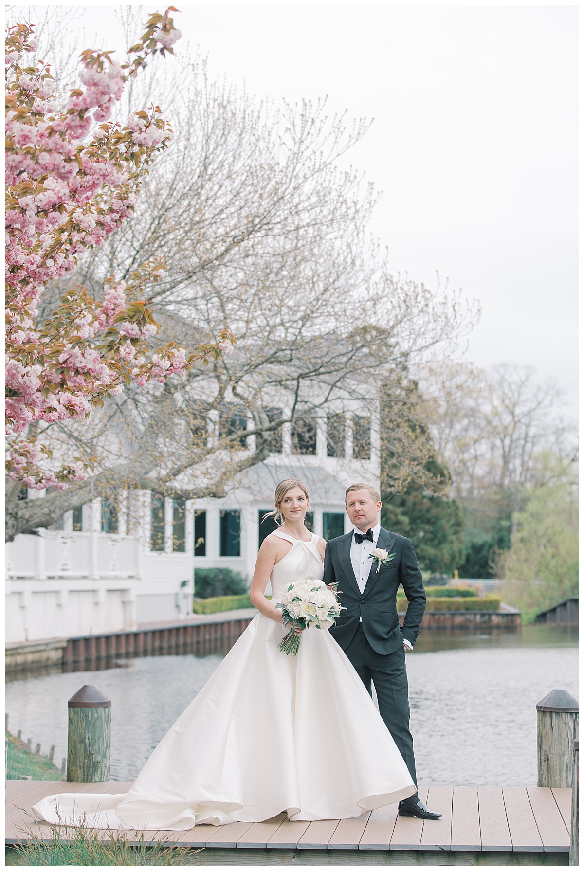 Bride and groom pose on dock of The Mill Lakeside Manor. 