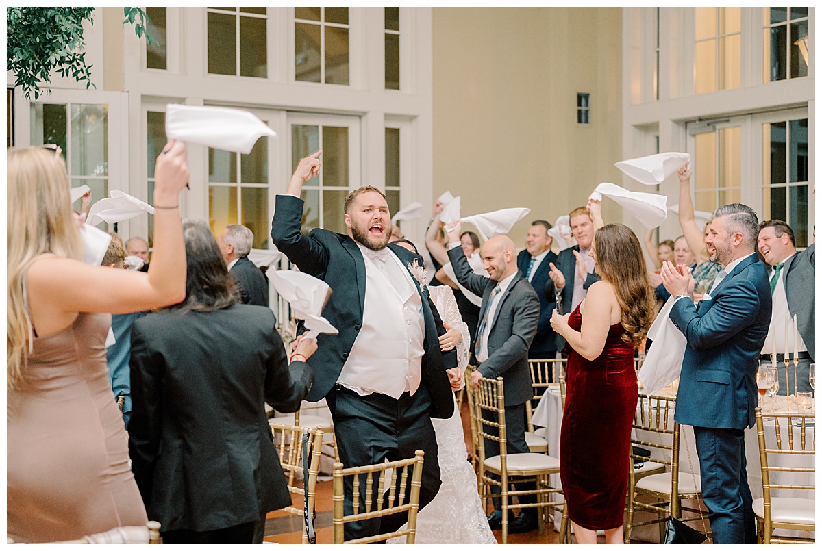 Guests swing their napkins as they welcome and cheer for the bride and groom. 