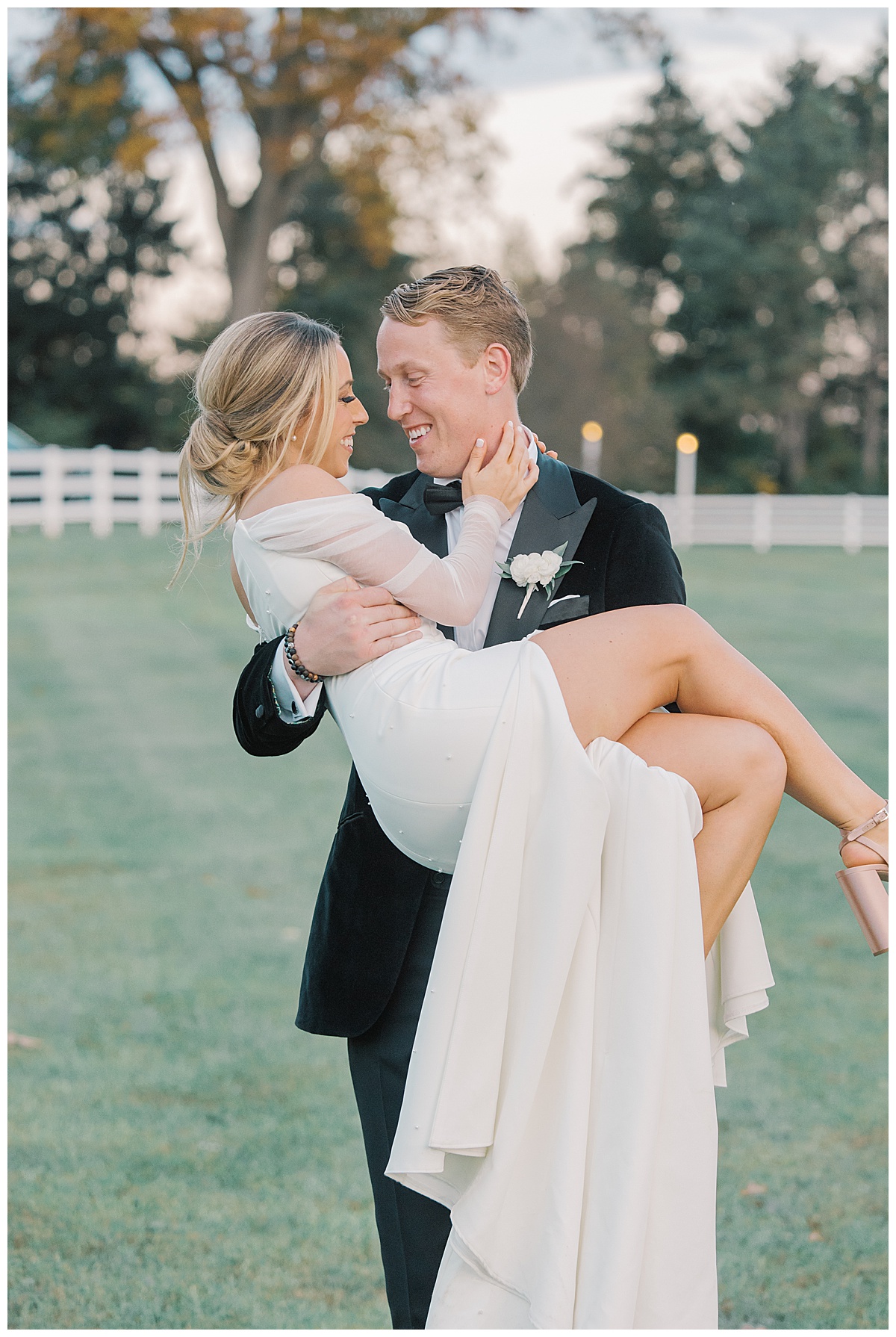 Groom scoops up bride and snuggles her tight in field.