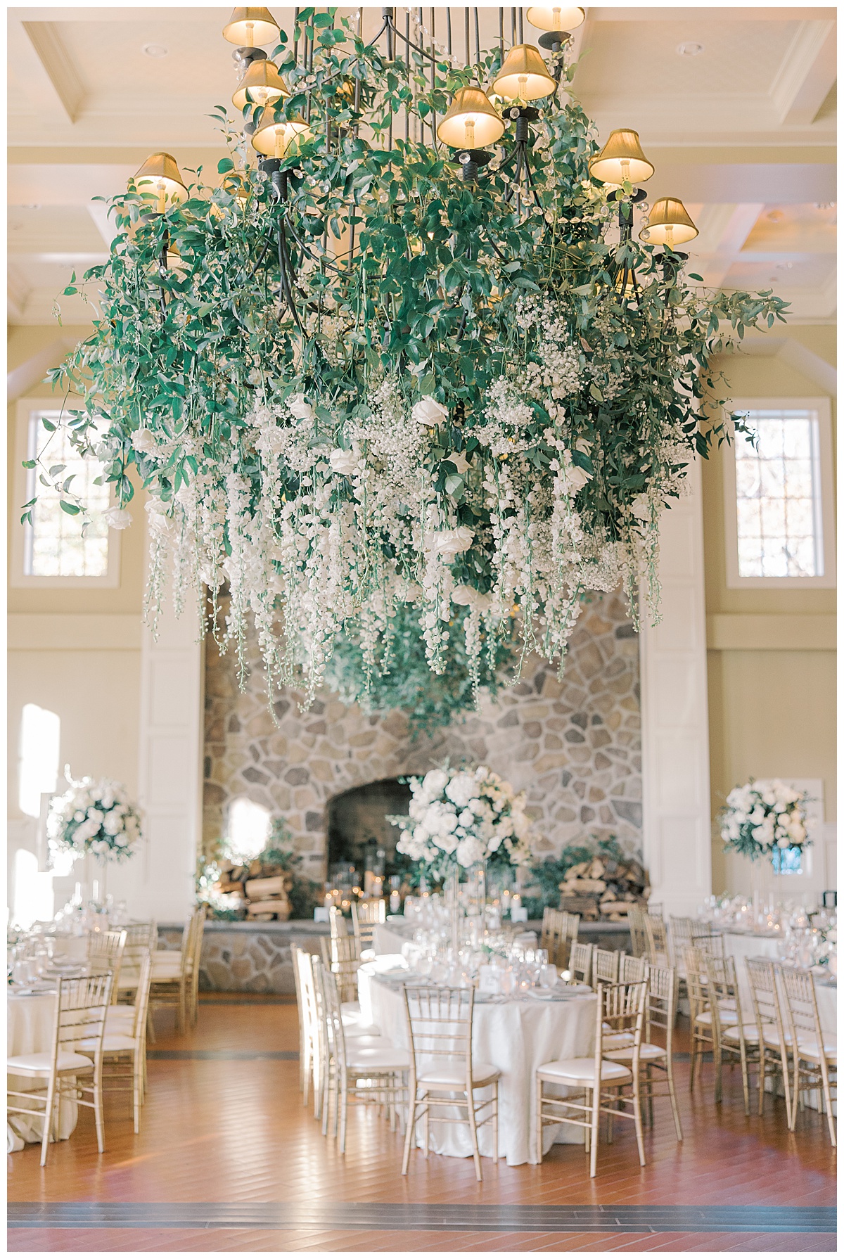 Large chandelier with tons of greenery and white florals hanging down at The Ryland Inn. 