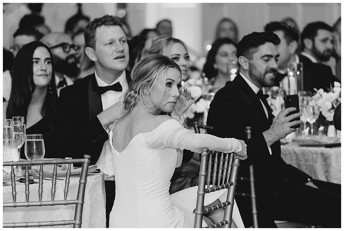 Bride wipes a tear from her eye as she watched the groom dance with his mom. 