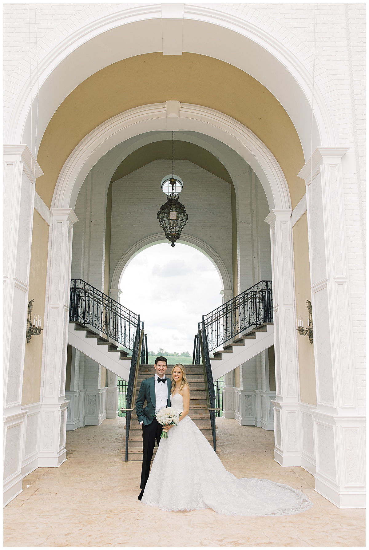 bride and groom smiling in front of stairs at Trump National Bedminster 