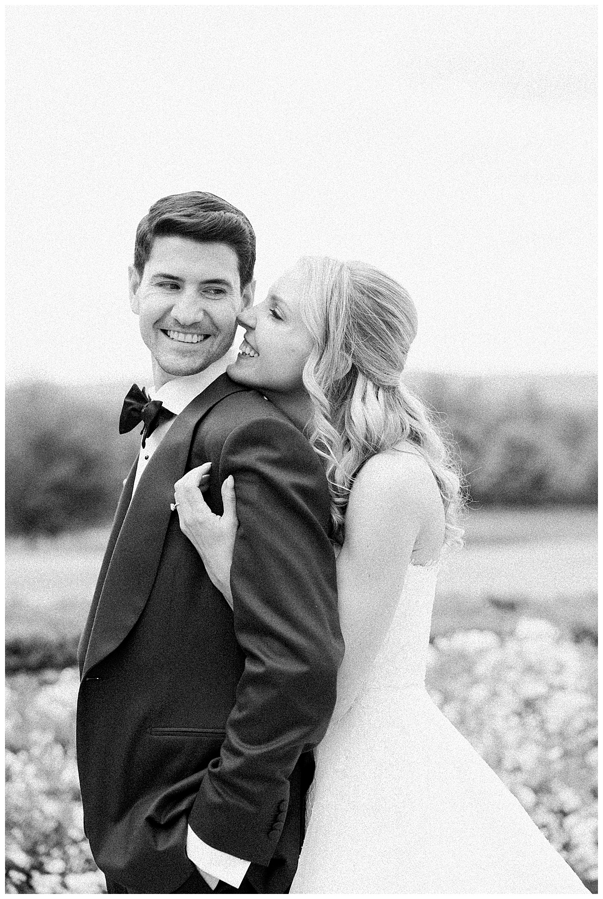 bride snuggling up to groom in a black and white image 
