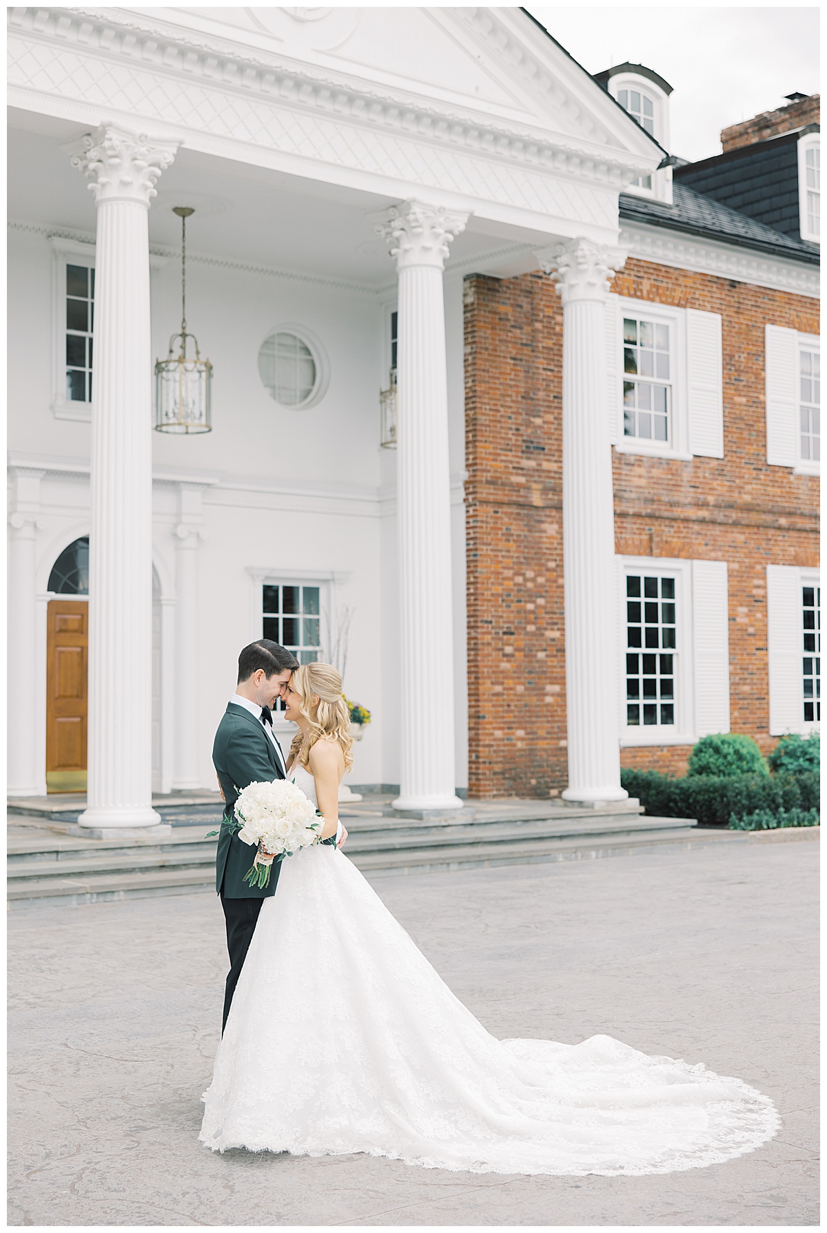bride and groom in front of columns and brick building on wedding day 