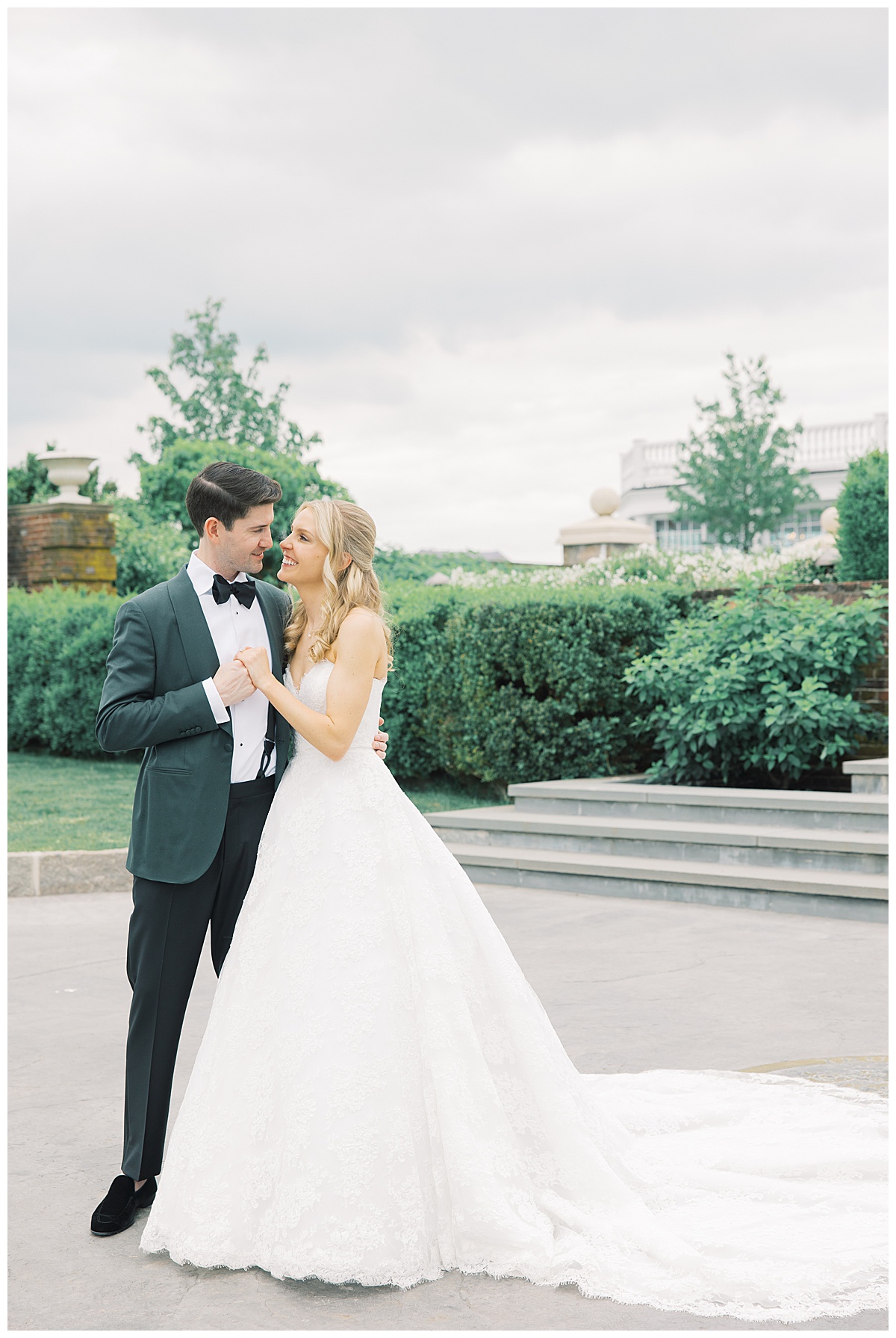 bride and groom looking at each other with lace gown and green tuxedo jacket 