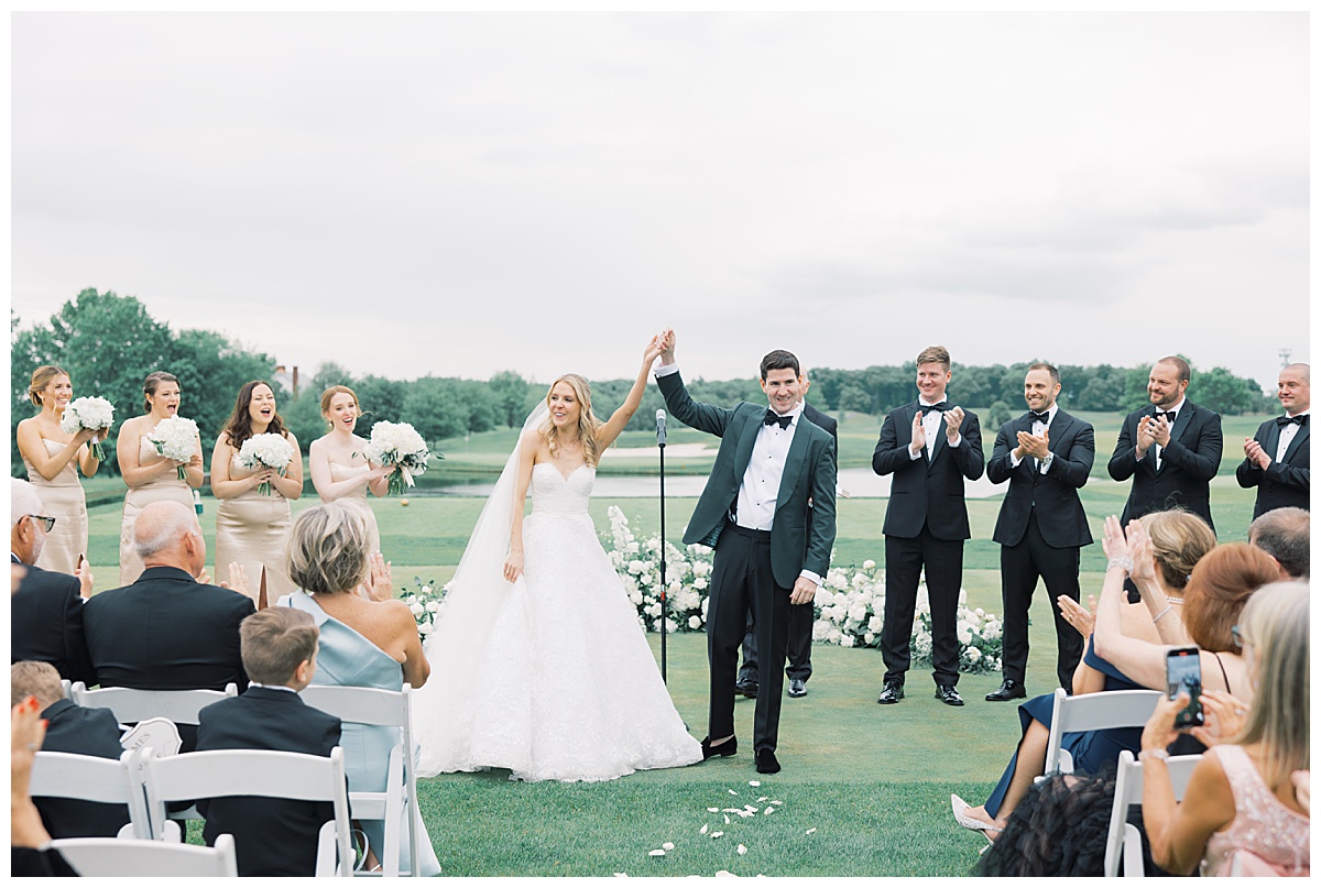 bride and groom cheer as they are announced as husband and wife with golf course behind them 