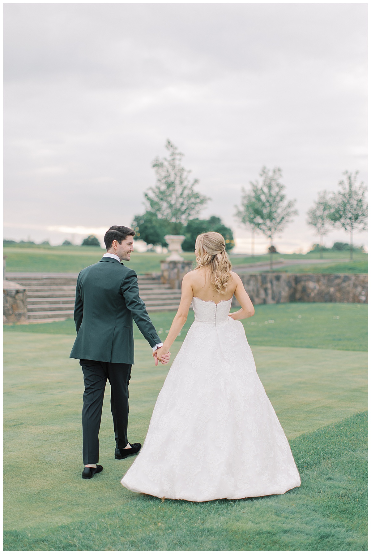 walking hand in hand with lace bridal gown on golf course 