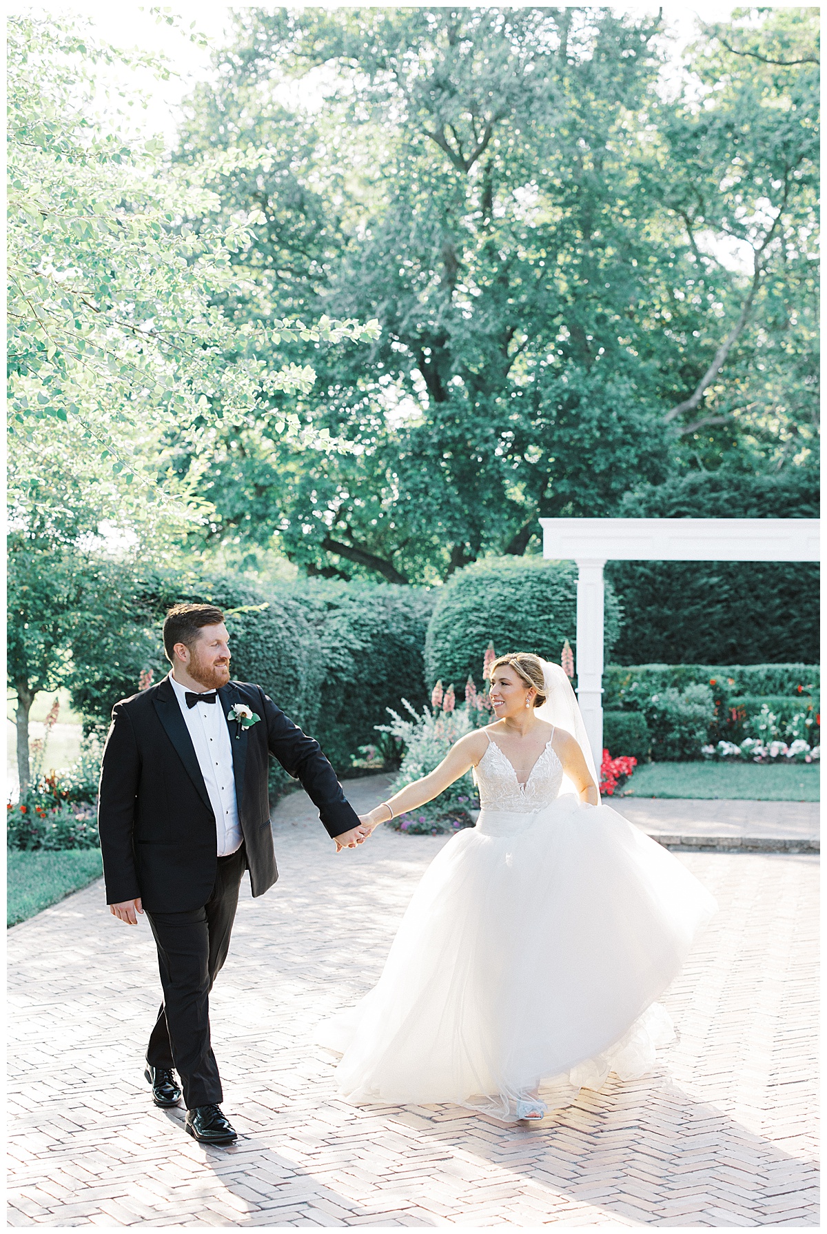 Bride and groom walk together as bride hikes up ballgown at The Mill Lakeside Manor.