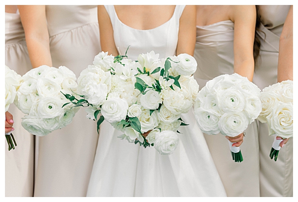 Bridesmaids holding white and green bouquets at the black tie wedding