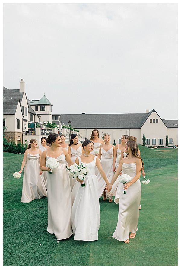 Bridesmaids in neutral toned dresses posing together on the wedding day