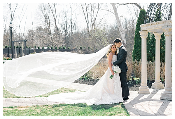 brides veil blowing in the wind with groom 