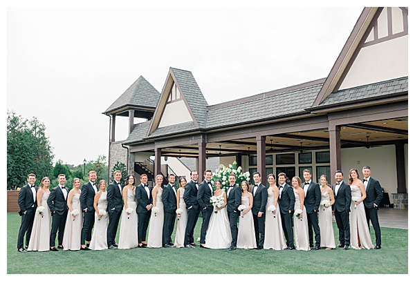Large bridal party dressed in black tie attire for the wedding celebration