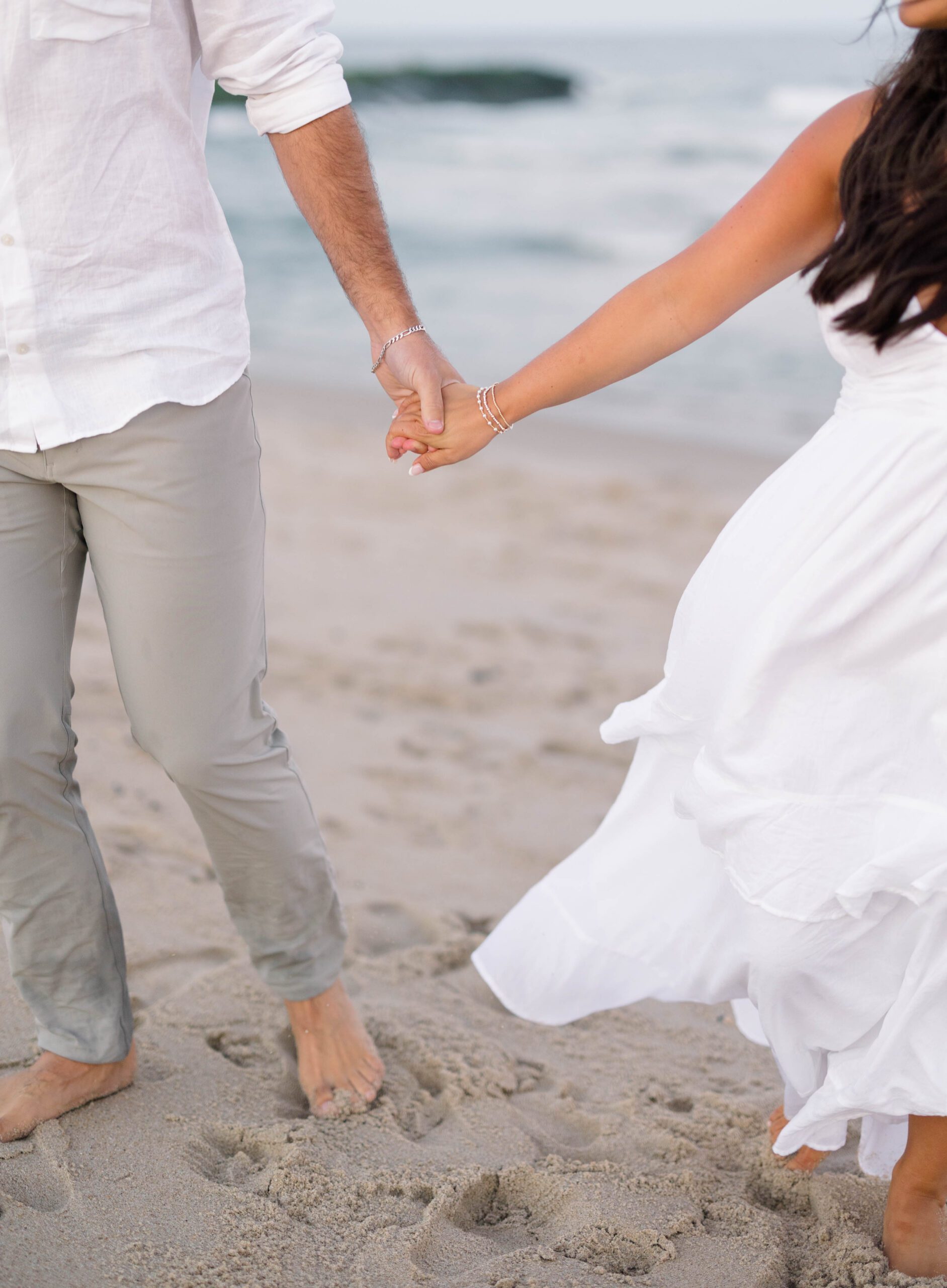 Monmouth County beach engagement session with couple holding hands on an uncrowded Spring Lake beach