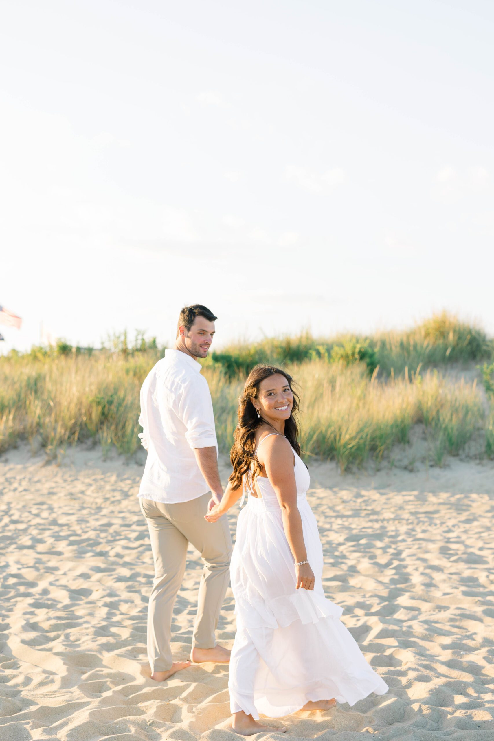 Spring Lake NJ beach engagement photos showing couple laughing as waves approach the shore
