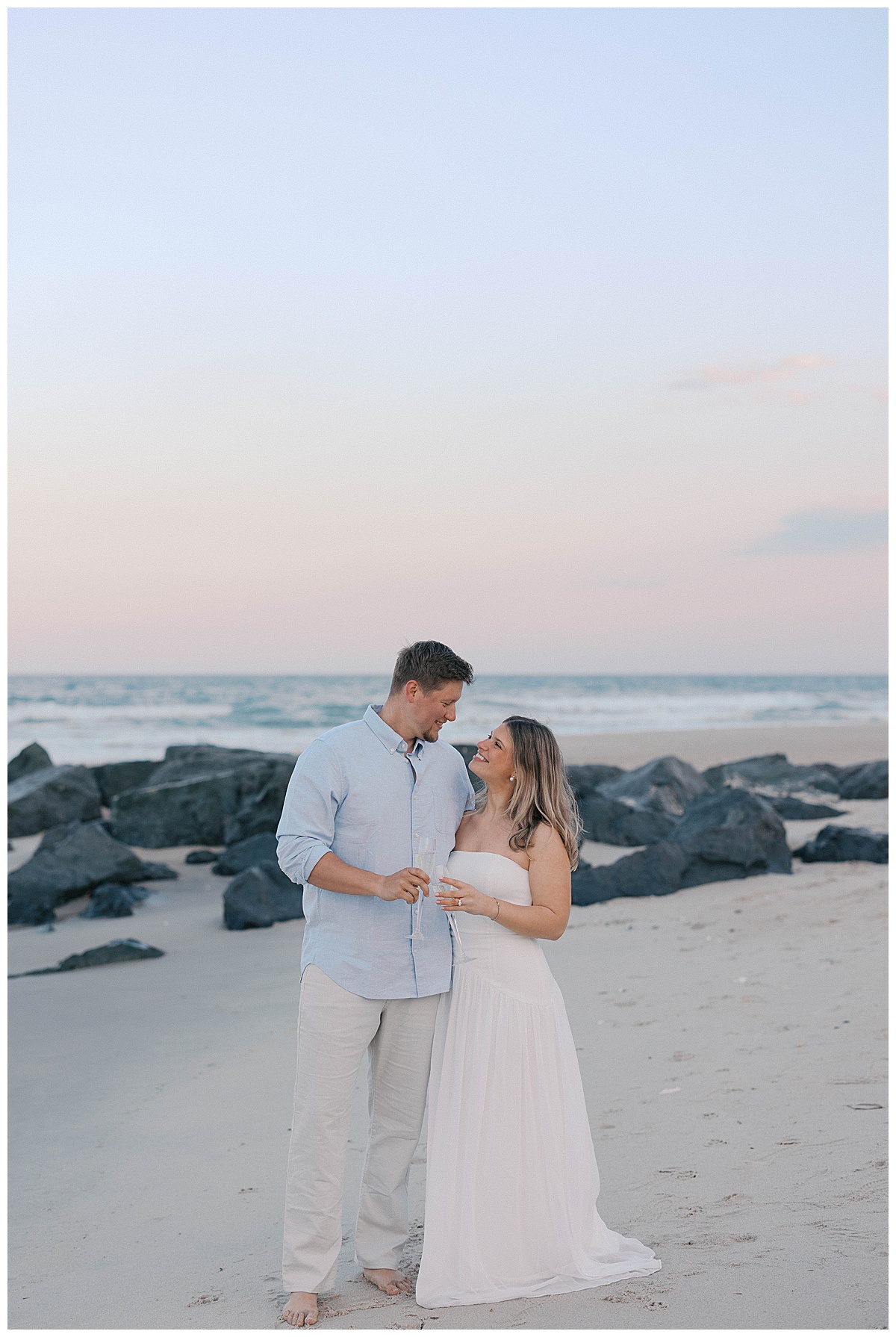 Editorial engagement photo of Amanda in a white dress on Sea Girt beach at sunset